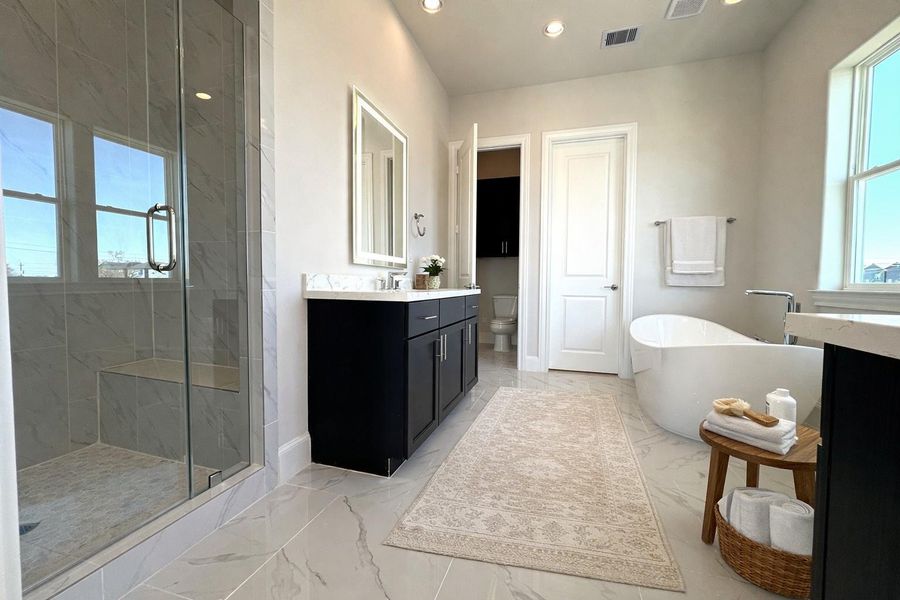 The naturally lit primary bathroom has separate shower and soaking tub. Virtual staging added.