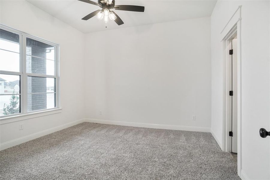 Empty room with light carpet and a ceiling fan