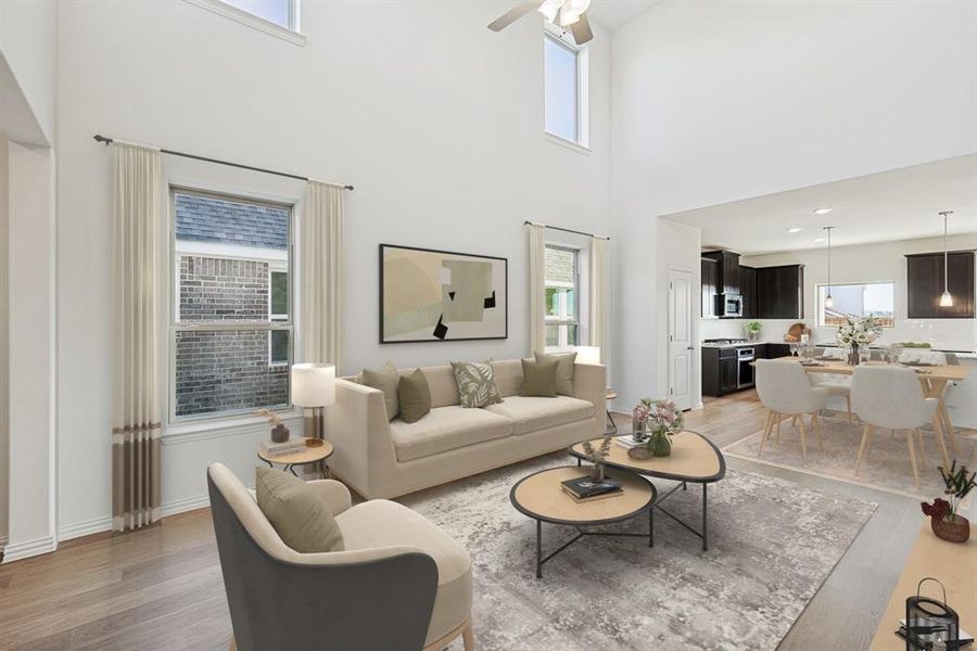 Living room featuring light wood-style floors, a towering ceiling, and a ceiling fan Living room featuring light wood-style floors, a towering ceiling, and a ceiling fan
