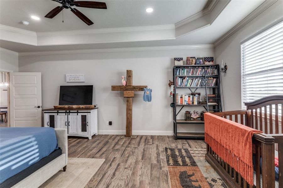 Bedroom featuring a raised ceiling, crown molding, wood finished floors, and recessed lighting