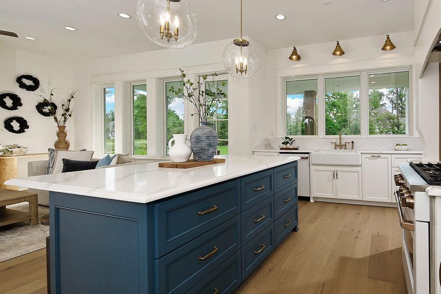 Premium quartz counters, farmhouse apron front sink, gold sconces tie cabinet pulls and pendant lights together perfectly. Windows above sink are gorgeous and convenient.
