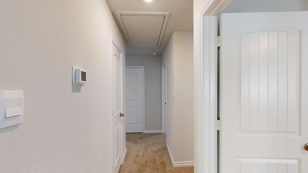 Hallway featuring light-colored walls, carpeted flooring, and white interior doors