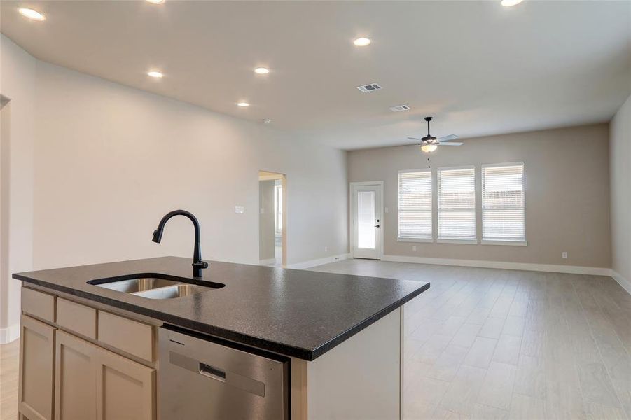 Kitchen featuring sink, dishwasher, ceiling fan, a kitchen island with sink, and light hardwood / wood-style floors