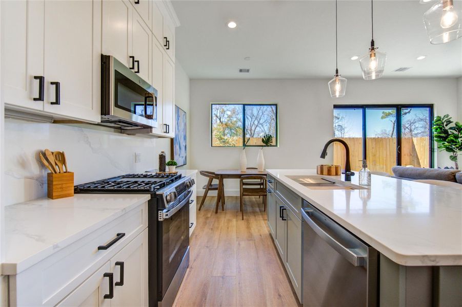 This modern kitchen features sleek white cabinetry, a spacious island with a built-in sink, and stainless steel appliances.