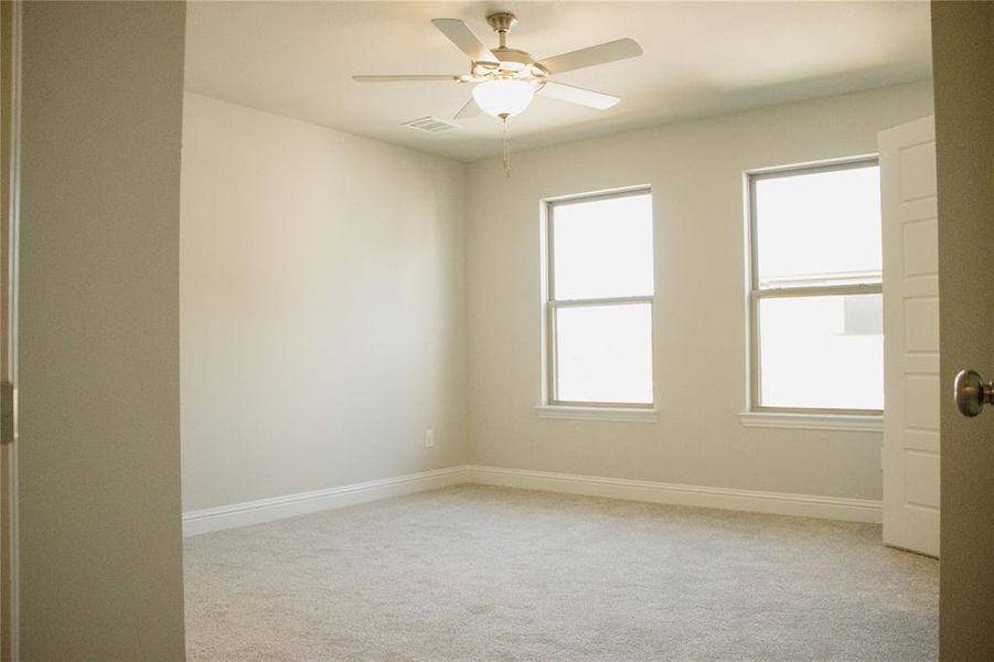 Carpeted empty room featuring ceiling fan