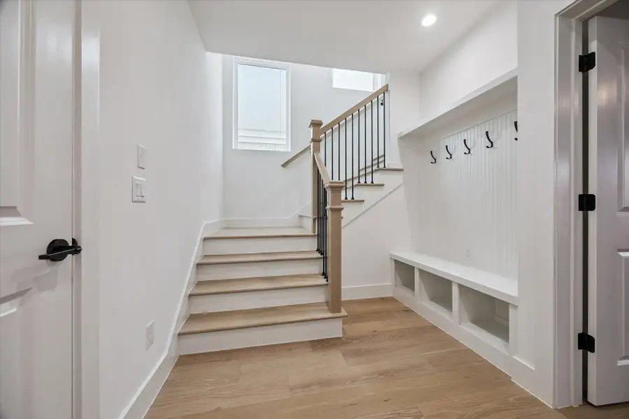 Welcoming entryway highlighted by a stunning staircase leading to the second-floor living space, along with a thoughtfully designed coat nook.
