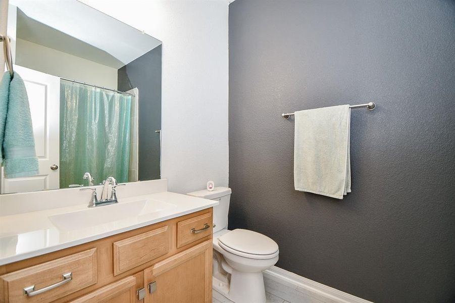 This full guest bathroom offers a single sink vanity, designer paint, and a convenient tub/shower enclosure.