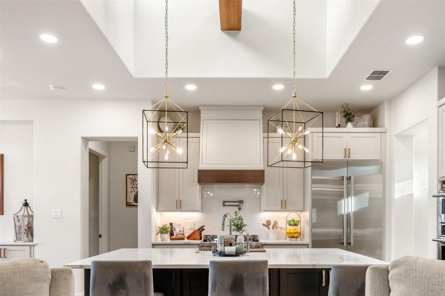 Kitchen featuring appliances with stainless steel finishes, decorative light fixtures, a kitchen island with sink, and white cabinets Kitchen featuring appliances with stainless steel finishes, decorative light fixtures, a kitchen island with sink, and white cabinets