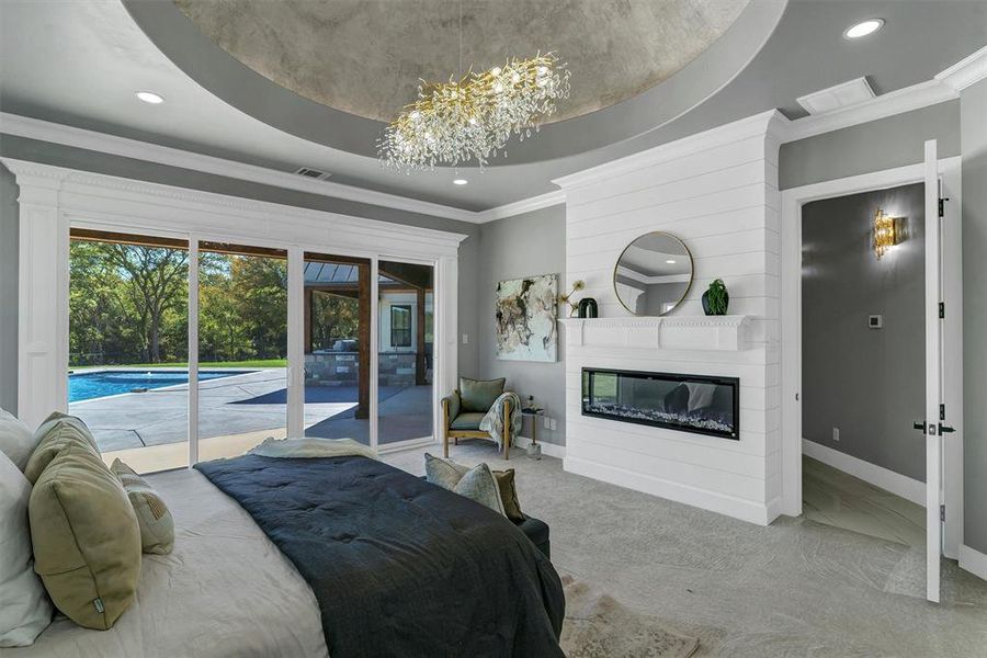 Bedroom with a notable chandelier, crown molding, access to outside, a tray ceiling, and light colored carpet