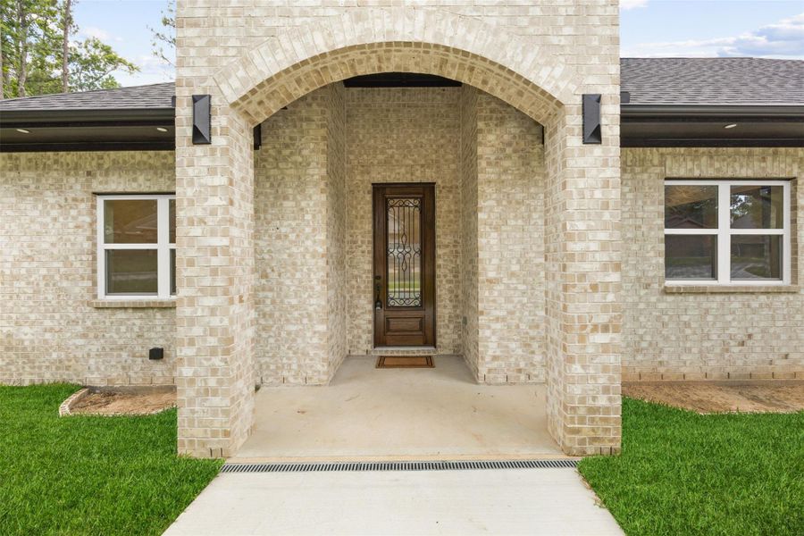 Inviting covered entry with brick archway.