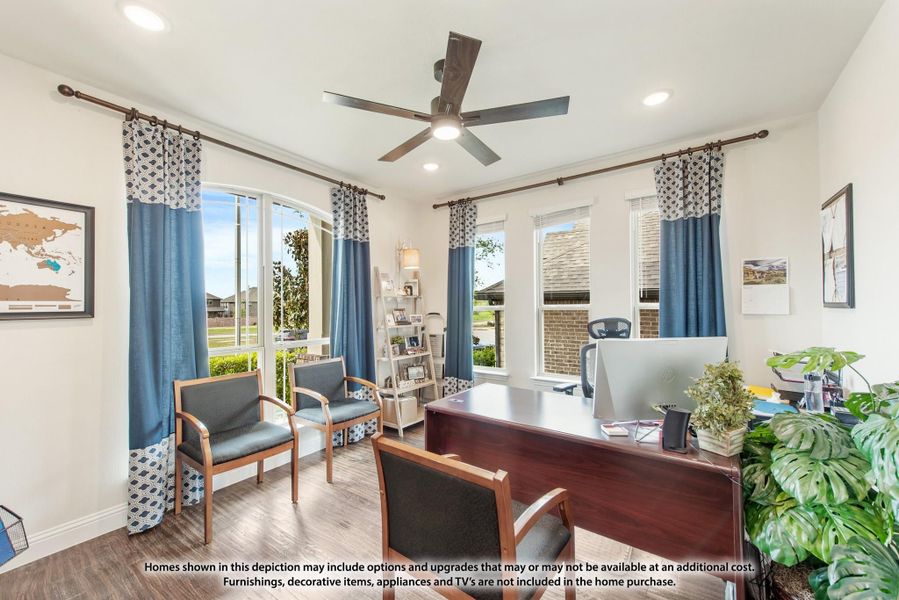 Home office with wood desk, ceiling fan, hardwood floors, and large windows with blue curtains