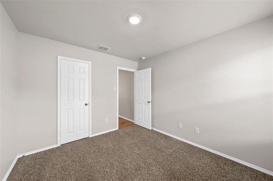 Unfurnished bedroom with dark carpet and baseboards Unfurnished bedroom with dark carpet and baseboards