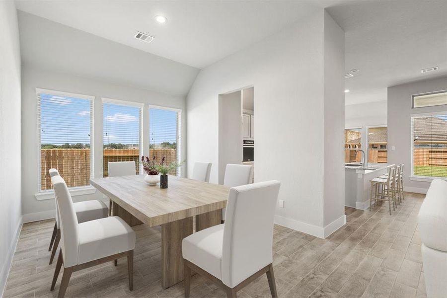 Craft enduring memories with loved ones around the table! This roomy dining area boasts stylish flooring, personalized paint, and is conveniently situated next to the family room and kitchen, fostering an open and inclusive ambiance. Sample photo of completed home with similar floor plan. As-built interior colors and selections may vary.