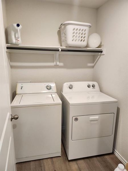 Laundry room with washer and clothes dryer and dark wood-type flooring