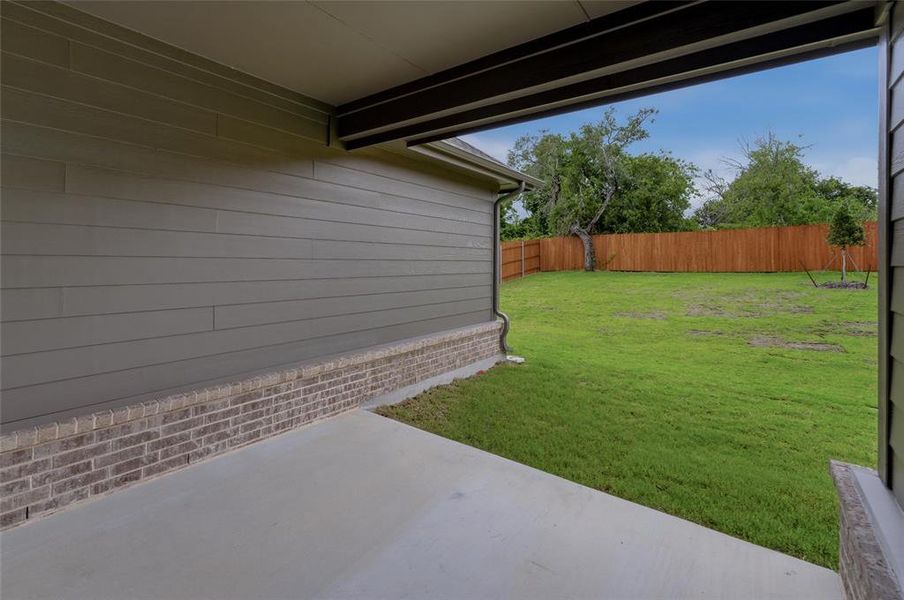 Covered patio with a concrete surface, featuring brick foundation and siding exterior