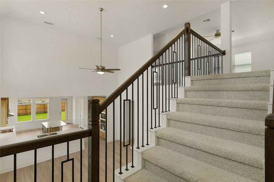 Staircase with a ceiling fan, wood finished floors, recessed lighting, and a high ceiling