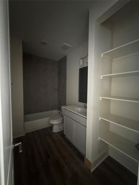 Bathroom featuring vanity, tub / shower combination, dark wood-type flooring, and a closet Bathroom featuring vanity, tub / shower combination, dark wood-type flooring, and a closet