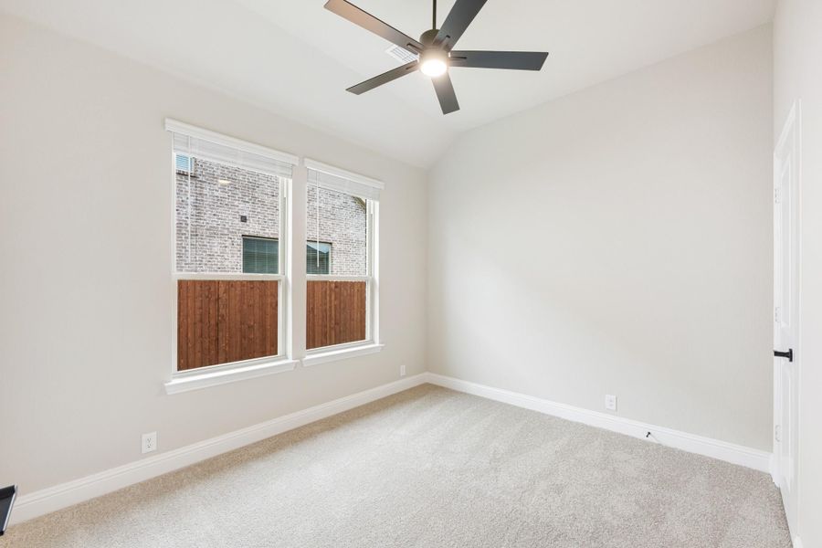 Empty bedroom with carpet flooring, ceiling fan, and double windows with white trim