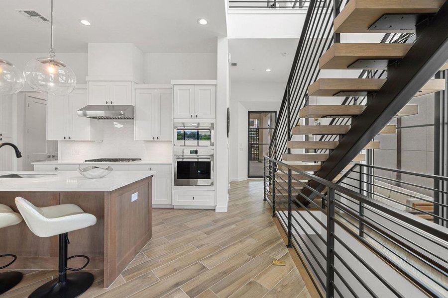 Modern kitchen and open-tread staircase featuring wood-finish flooring