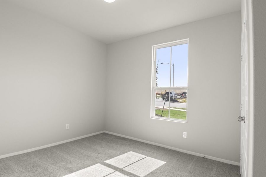 Image of a bedroom with tan carpeting and light grey walls with a large winow