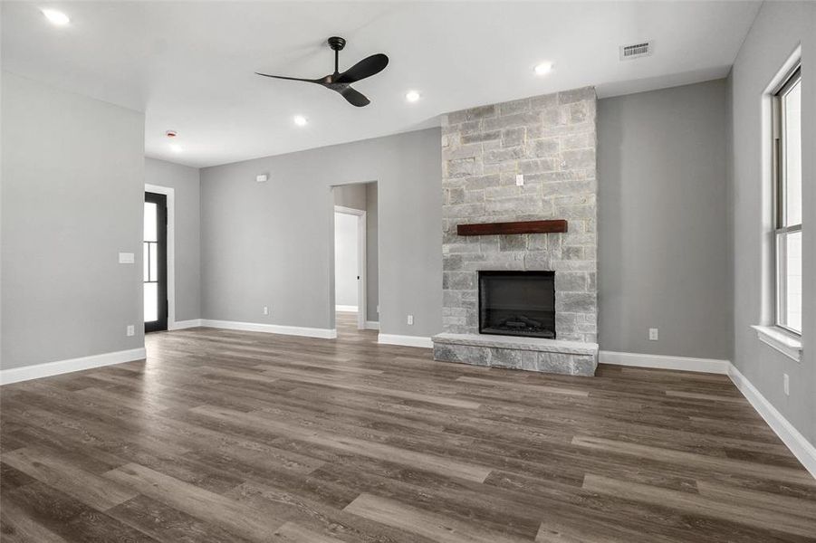 Unfurnished living room featuring a ceiling fan, a stone fireplace, dark wood-style floors, and recessed lighting Unfurnished living room featuring a ceiling fan, a stone fireplace, dark wood-style floors, and recessed lighting