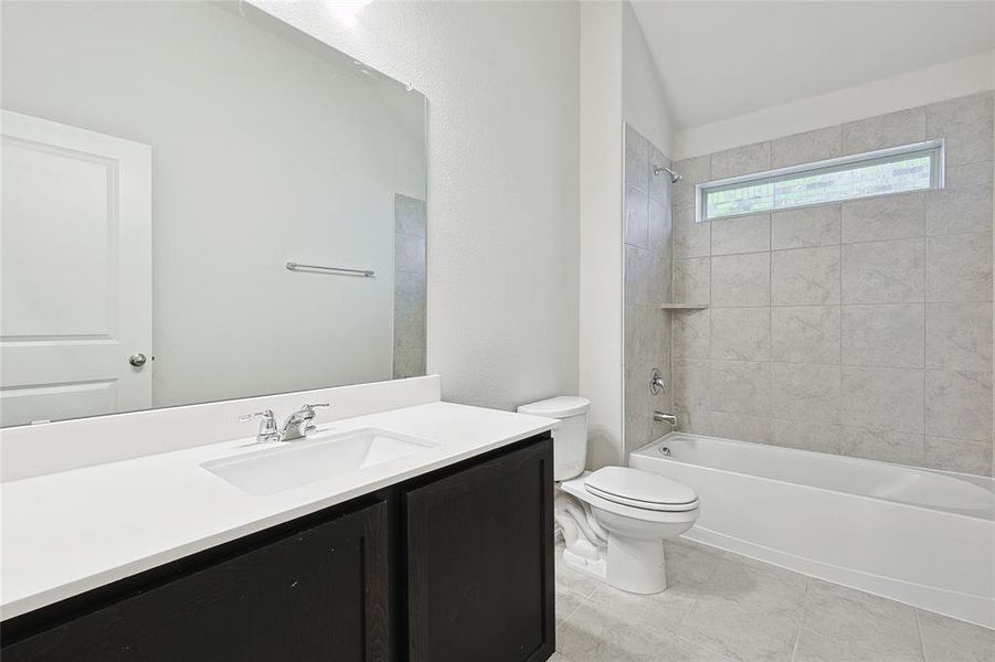 Full bathroom with tile patterned floors, toilet, vanity, and tiled shower / bath