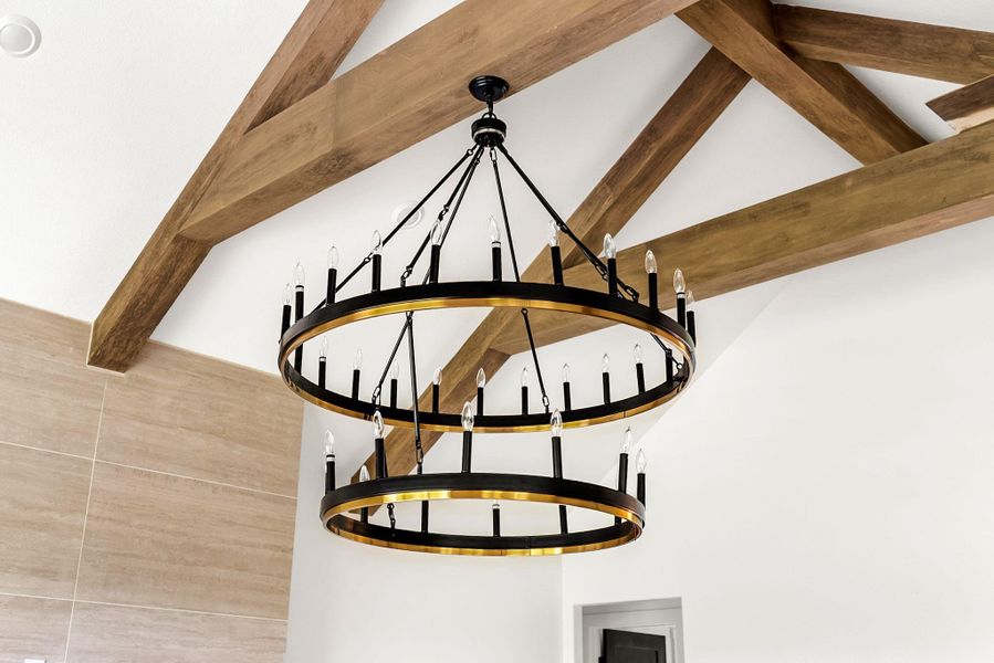 Dramatic exposed wood beams crown this space, complemented by a striking two-tiered chandelier.