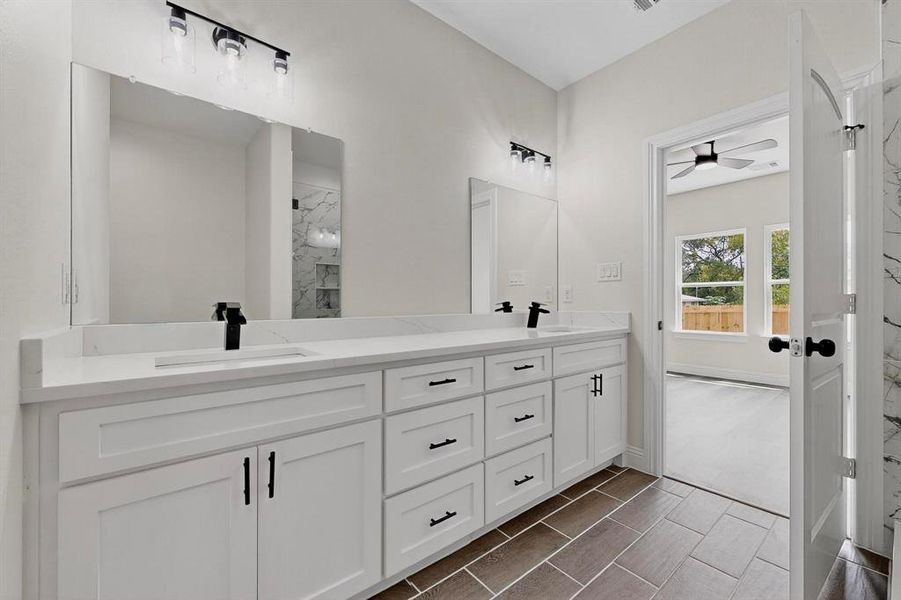 Full bathroom with double vanity, a marble finish shower, and a ceiling fan Full bathroom with double vanity, a marble finish shower, and a ceiling fan