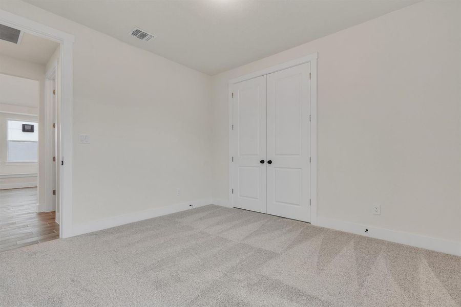 A well-lit room with soft carpeting offers a versatile space, perfect for any need.
