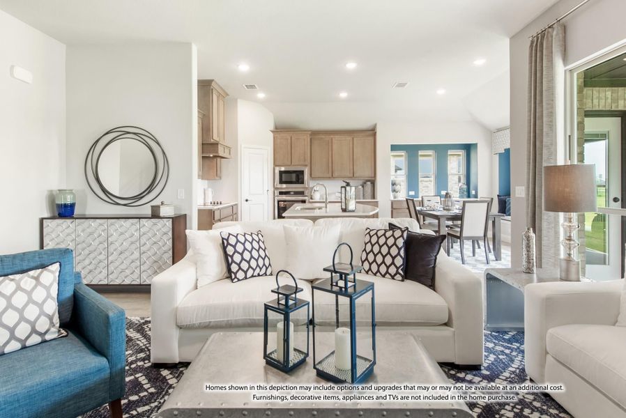 Open-concept living room with white sofa, blue accents, and kitchen visible in background Open-concept living room with white sofa, blue accents, and kitchen visible in background