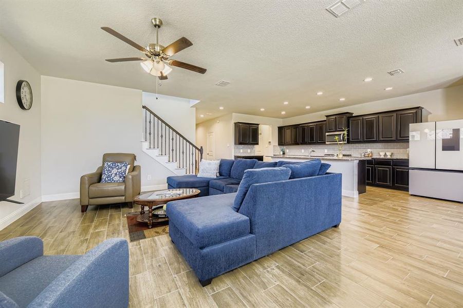Living area featuring wood finish floors, recessed lighting, stairway, a textured ceiling, and a ceiling fan Living area featuring wood finish floors, recessed lighting, stairway, a textured ceiling, and a ceiling fan