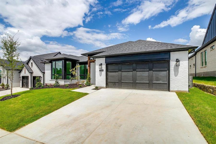 View of front of property featuring a garage, a front lawn, and central AC unit