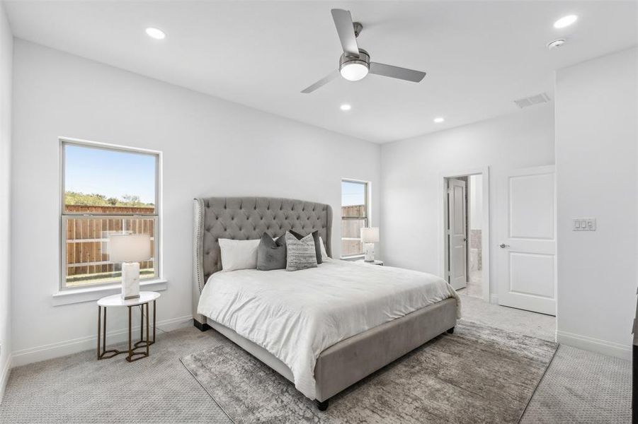 Bedroom with ceiling fan, connected bathroom, and light colored carpet