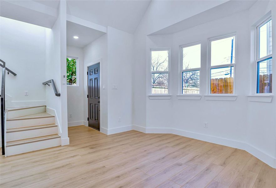 Unfurnished room with lofted ceiling, stairway, baseboards, and wood finished floors