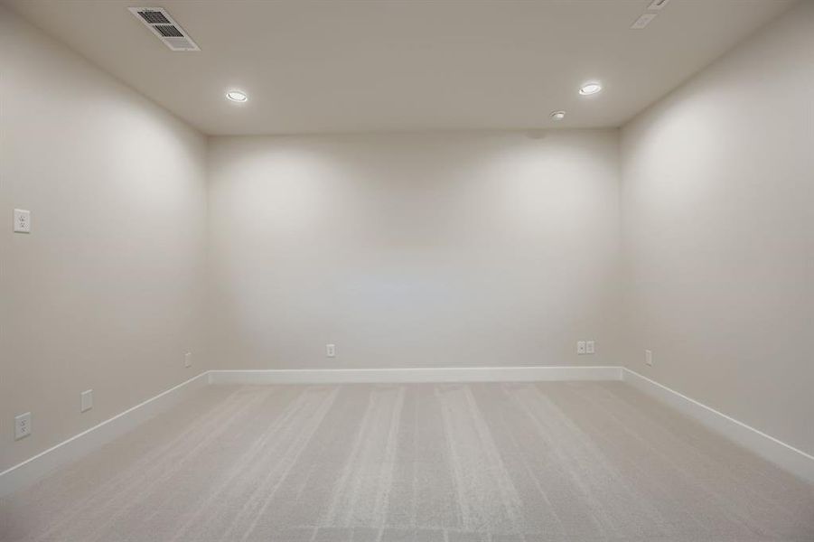 Empty room with light colored carpet and recessed lighting