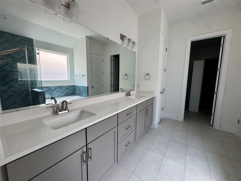 Bathroom featuring a garden tub, double vanity, a shower stall, and light tile patterned floors