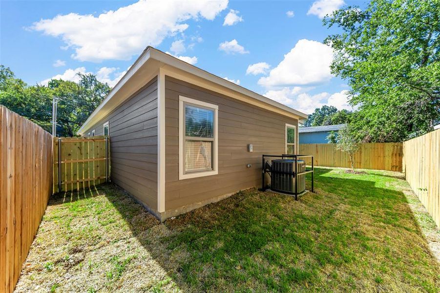 Rear view of property featuring a lawn and central AC unit