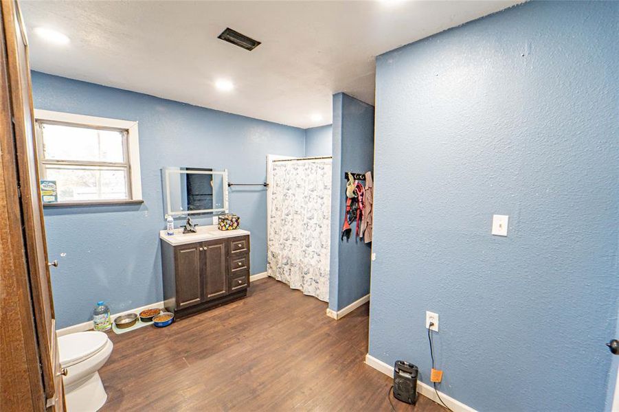 Bathroom with a shower with curtain, a textured wall, vanity, dark wood finished floors, and recessed lighting Bathroom with a shower with curtain, a textured wall, vanity, dark wood finished floors, and recessed lighting