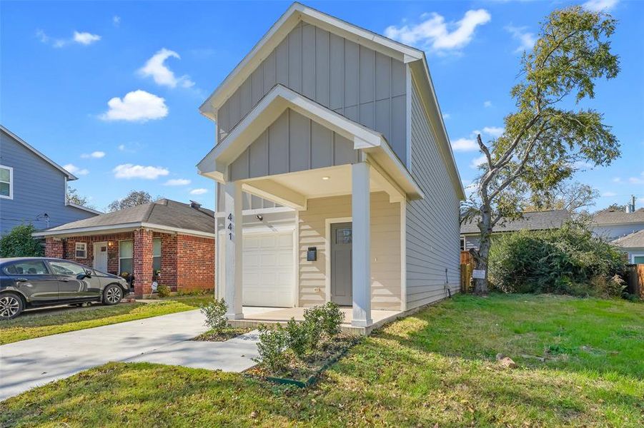 View of front of house featuring board and batten siding, a front lawn, driveway, a garage, and a porch