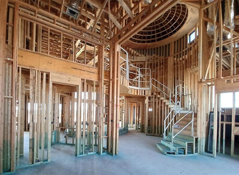 View from the Dining Room and Foyer with sites into the elevated two-story Living area and stunning winding staircase with curved catwalk, and domed ceiling with lots of architectural appeal is coming along well.