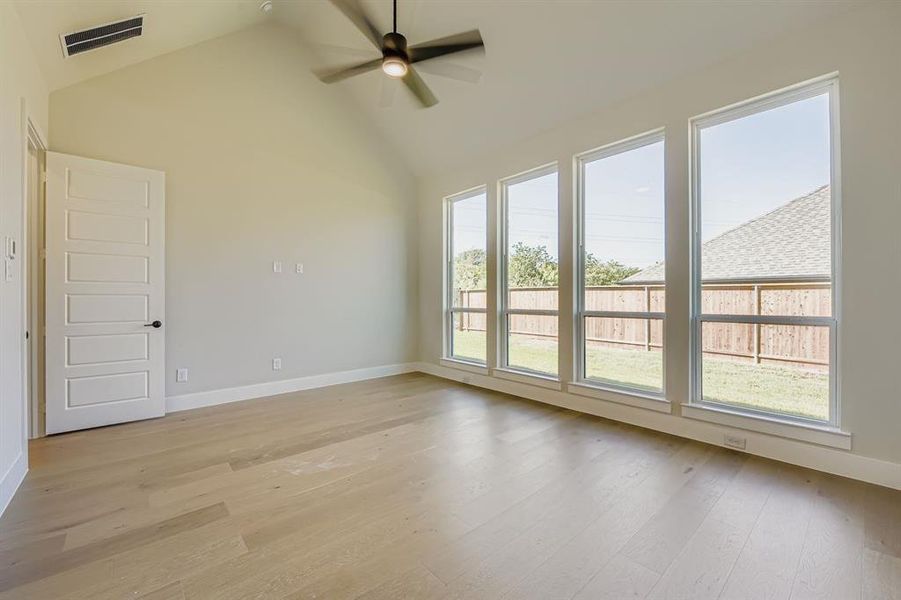 Unfurnished room featuring light wood-style flooring, ceiling fan, and high vaulted ceiling