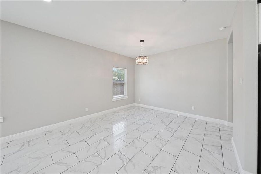 Spare room featuring light marble finish flooring and a chandelier