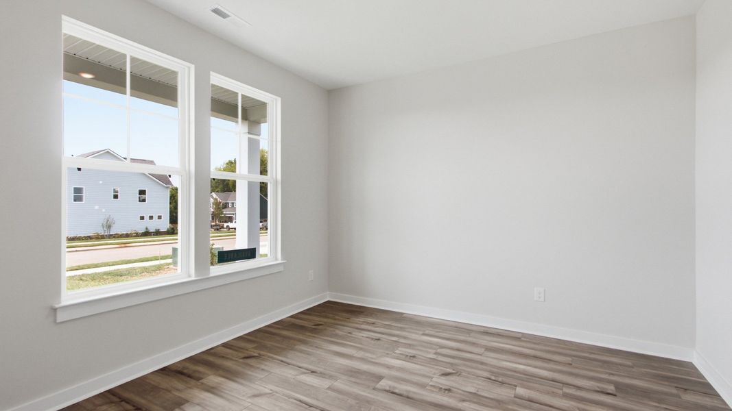 Front room with windows illuminating wood floors and spacious setting
