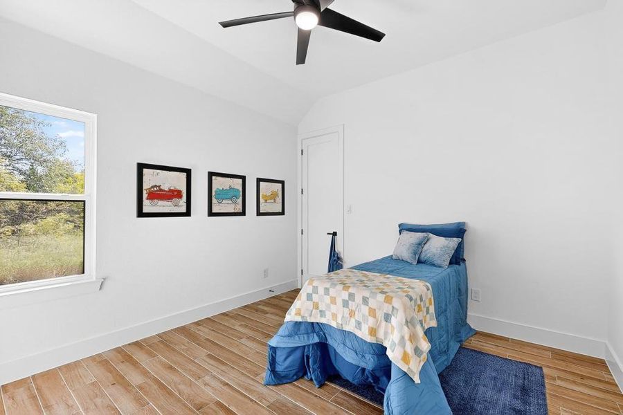 Bedroom featuring lofted ceiling, wood finished floors, and ceiling fan