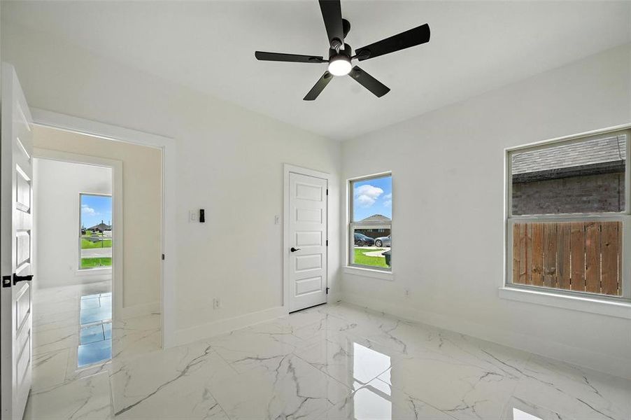 Spare room featuring marble finish flooring and a ceiling fan