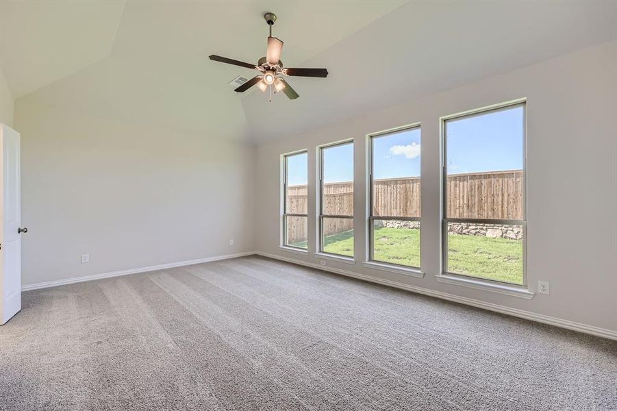 Primary bedroom with ceiling fan, high vaulted ceiling, and carpet