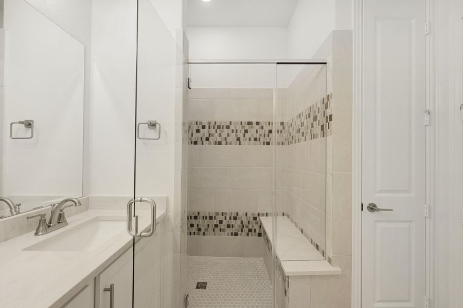Bathroom with glass walk-in shower, mosaic tile accents, built-in bench, and white vanity with quartz countertop