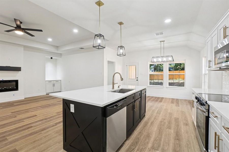 Kitchen with dark cabinets, white cabinets, appliances with stainless steel finishes, open floor plan, and pendant lighting Kitchen with dark cabinets, white cabinets, appliances with stainless steel finishes, open floor plan, and pendant lighting