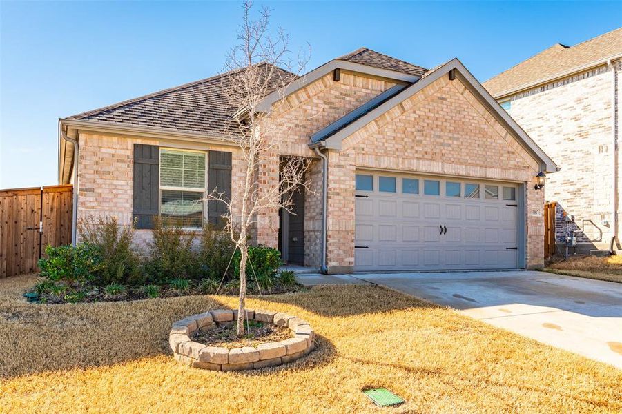 View of front of property with concrete driveway, brick siding, fence, and an attached garage