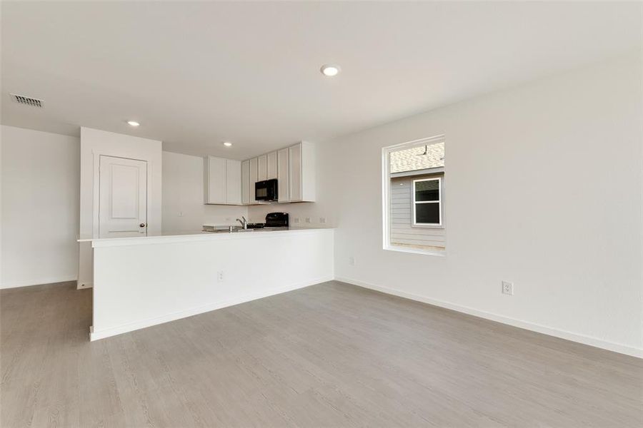 Kitchen with white cabinets, a peninsula, recessed lighting, light wood-style floors, and light countertops